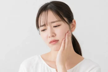 矯正で歯が痛くて顎を抑える女性